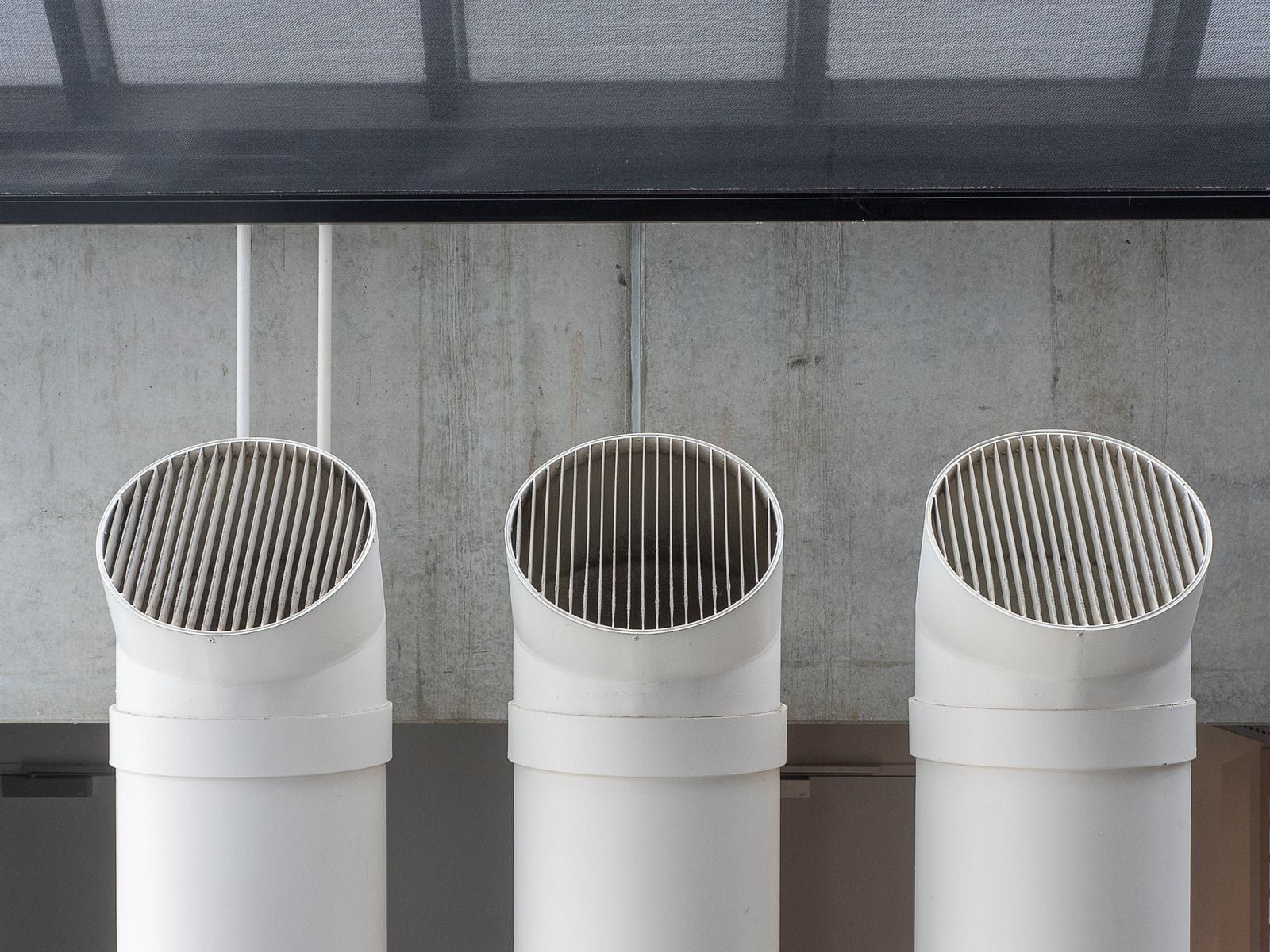 Conduits de ventilation ronds sortant d’un plafond en béton