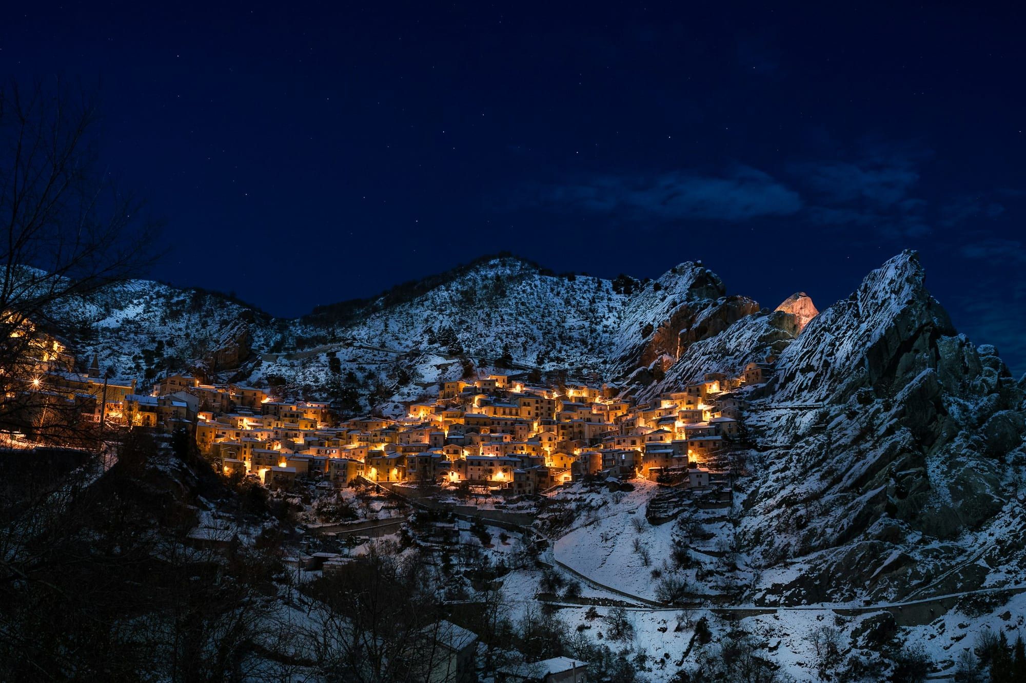 Village de montagne éclairé la nuit, sous la neige